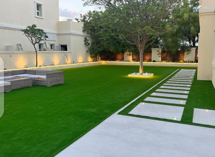 Completed artificial grass villa garden installation in Dubai with pathway lighting and outdoor seating